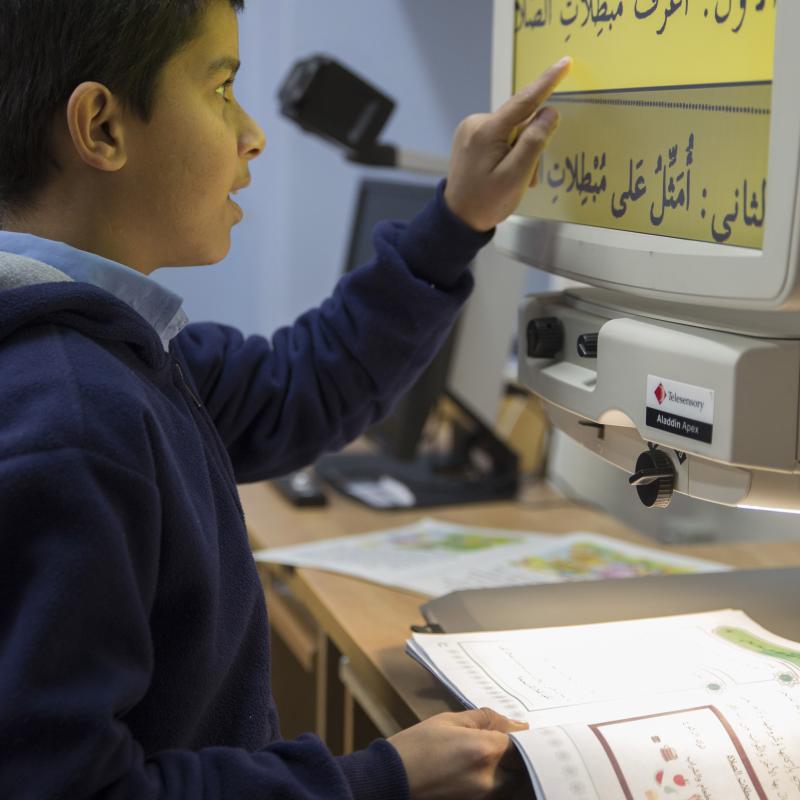 13岁的阿米尔·凯西耶(Amir Qaisiyyeh)在巴勒斯坦盲人慈善协会学校上课时，通过阅读辅助工具阅读投影在电脑屏幕上的放大文本。